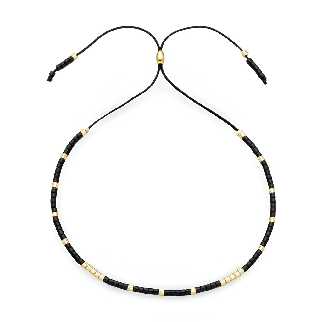 Bracelet Tsunada pour femme en perles noires et dorées sur cordon noir réglable.