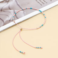 Bracelet fin en perles turquoise, rose et or avec fermeture coulissante ajustable.