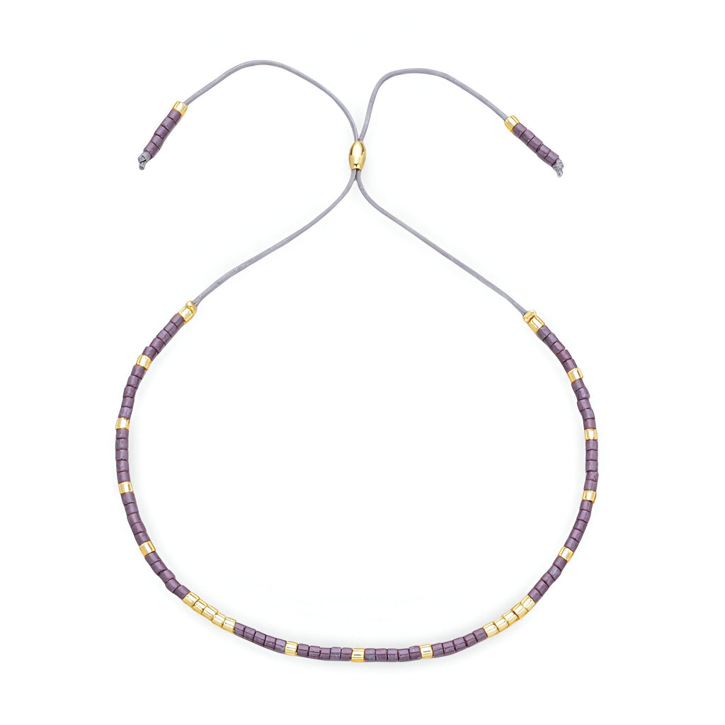 Bracelet Tsunada pour femme en perles japonaises violettes et dorées réglable par cordon gris.