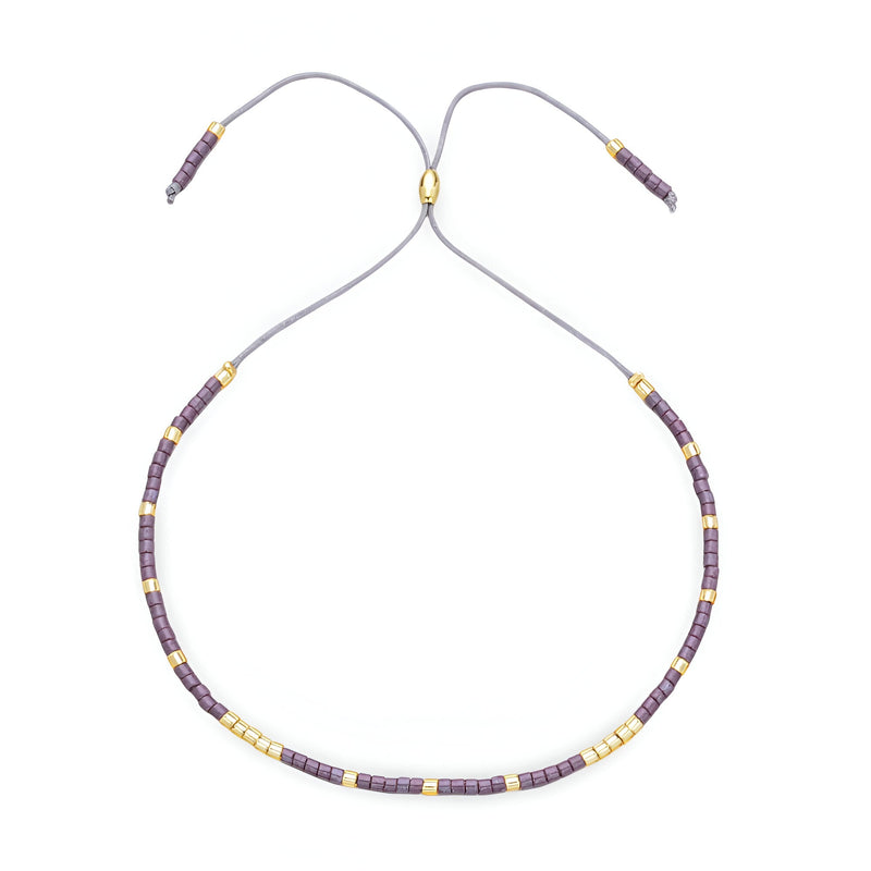 Bracelet Tsunada pour femme en perles japonaises violettes et dorées réglable par cordon gris.