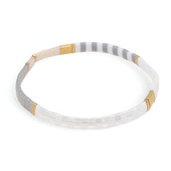 Bracelet fin en perles blanches et grises avec accents dorés, style minimaliste et élégant.