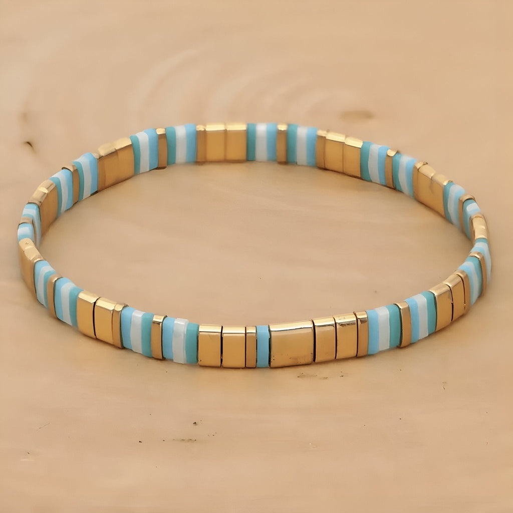 Bracelet élastique pour femme en perles bleues, blanches et dorées, style minimaliste japonais.