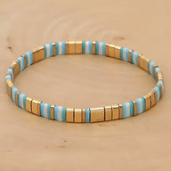 Bracelet élastique pour femme en perles bleues, blanches et dorées, style minimaliste japonais.
