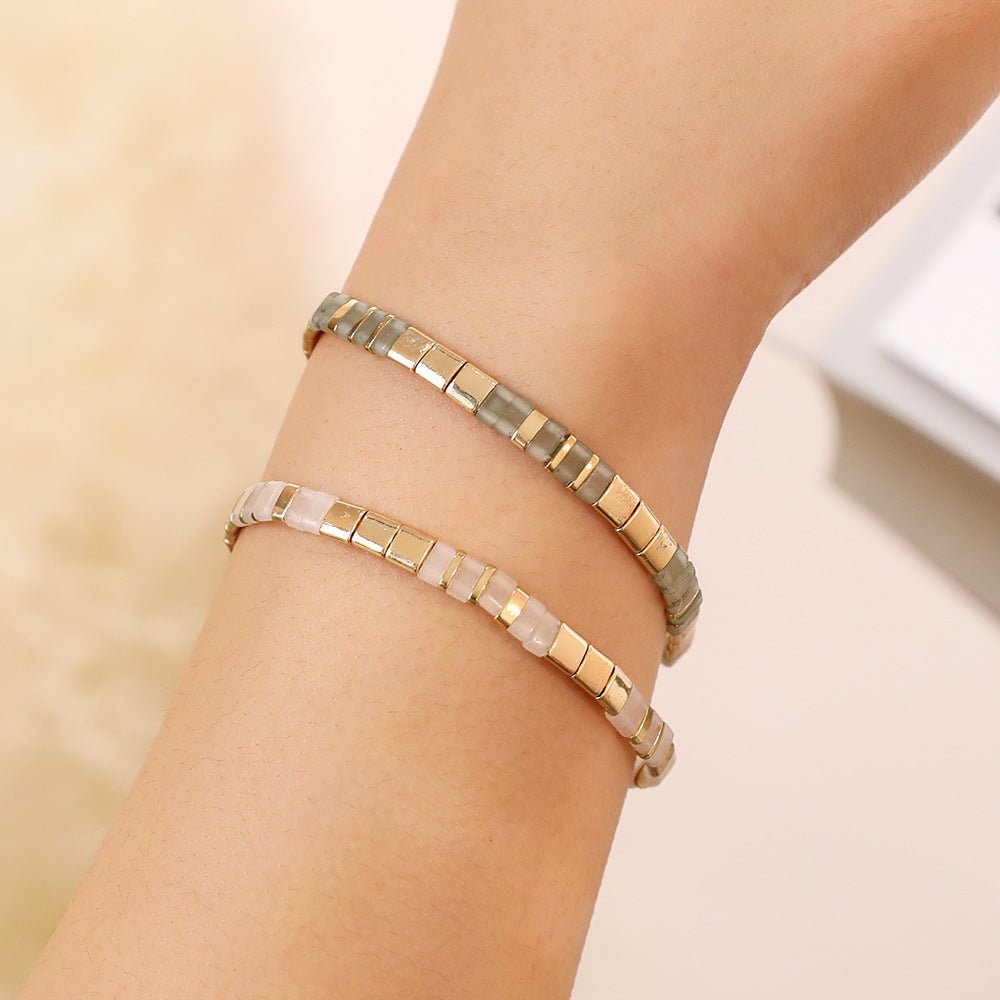 Bracelet souple à enfiler avec perles carrées dorées et perles rondes multicolores sur peau pâle.