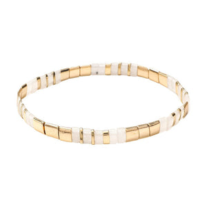 Bracelet souple à enfiler en perles dorées et blanches rectangulaires, style minimaliste et lumineux.