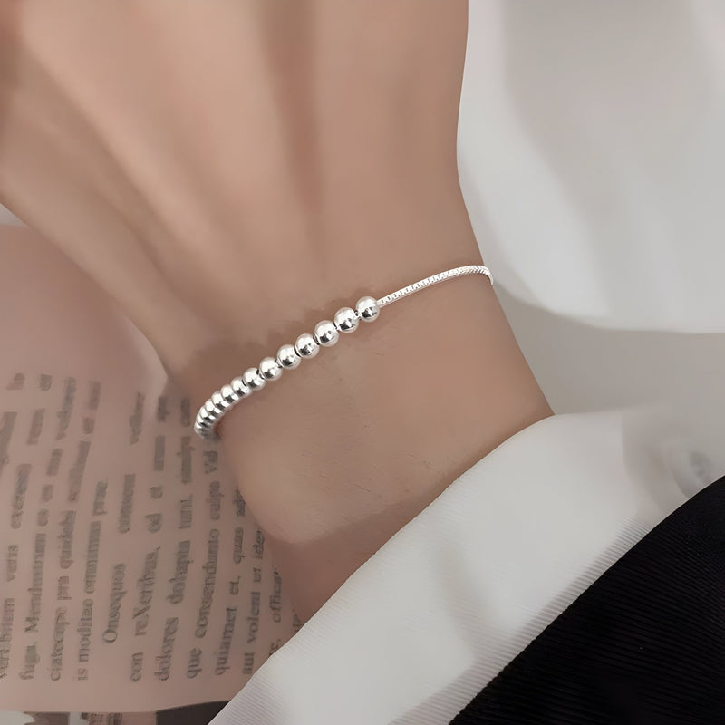Bracelet fin en argent sterling avec perles brillantes sur un fil délicat.