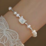 Bracelet blanc en perles avec tête de chat en argent sterling sur poignet féminin.