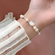 Bracelet en perles blanches avec tête de chat en argent sterling sur poignet féminin.