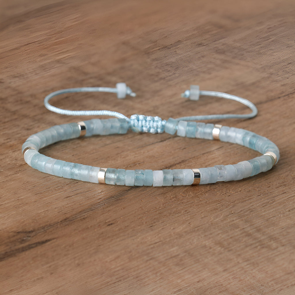 Bracelet ajustable perles heishi aigue-marine bleu clair avec intercalaires argentés sur cordon fin blanc.