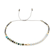 Bracelet femme perles heishi multicolores avec détails en cristal et fermoir coulissant gris.