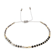 Bracelet réglable perles heishi noires et grises avec petits cristaux dorés et argentés.