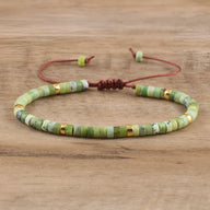 Bracelet ajustable en perles heishi vertes en jade australienne avec détails dorés sur cordon marron.