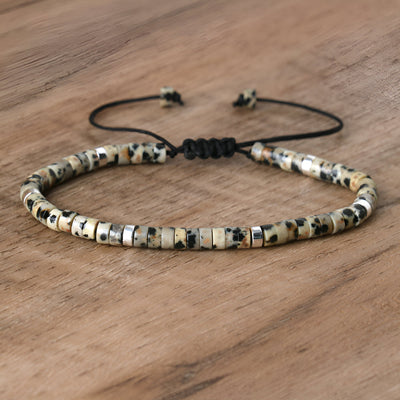 Bracelet mixte en perles heishi jaspe dalmatien blanches avec cordon noir réglable.