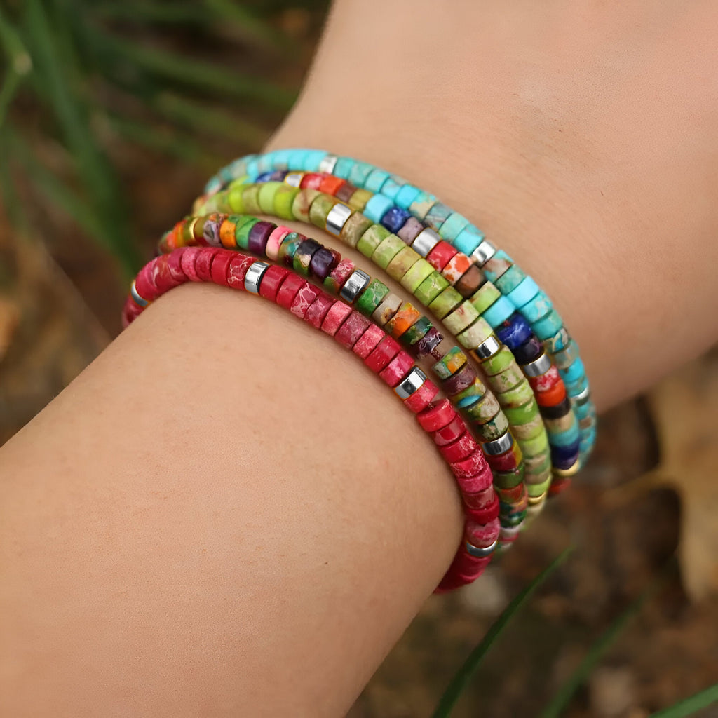 Bracelets en perles heishi multicolores et rouge en jaspe, style mixte, portés au poignet.