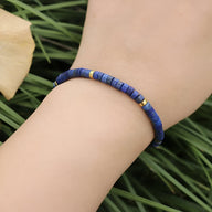 Bracelet mixte en perles heishi bleu lapis lazuli avec détails en métal doré.