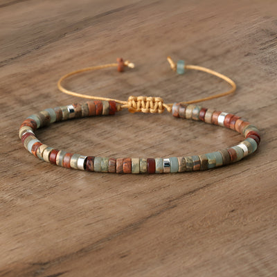 Bracelet mixte en perles heishi multicolores avec détails métalliques dorés sur cordon rigide.