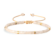 Bracelet mixte en perles heishi blanches avec détails dorés et fermoir coulissant doré.