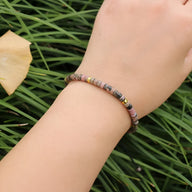 Bracelet fin en perles heishi rhodonite tachetée rose avec détails en métal doré.