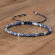 Bracelet mixte perles heishi sodalite bleu avec détails métal argenté et cordon réglable noir.