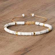 Bracelet mixte en perles heishi blanches howlite avec détails dorés et fermeture coulissante cordon beige.