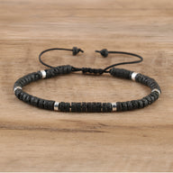 Bracelet mixte avec perles heishi noires en pierre volcanique et détails métalliques argentés, cordon réglable.