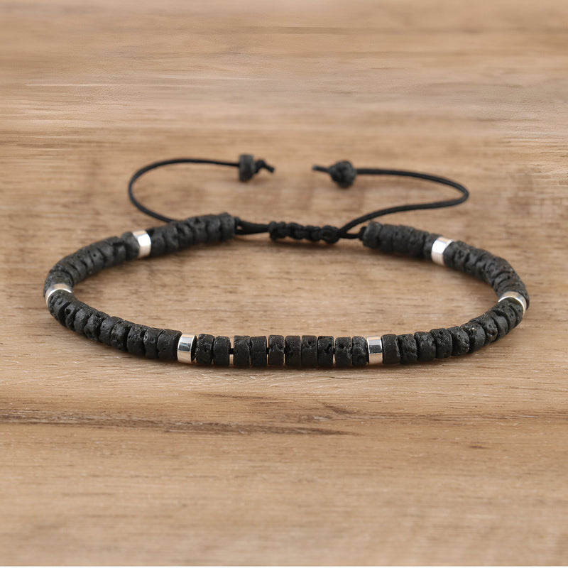 Bracelet mixte avec perles heishi noires en pierre volcanique et détails métalliques argentés, cordon réglable.