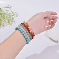 Bracelets en perles rondes multicolores bleu turquoise, rose, vert, et rouge portés sur poignet féminin.