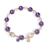 Bracelet pour femme en pierres rondes d'améthyste violet profond avec perles dorées et breloques scintillantes.