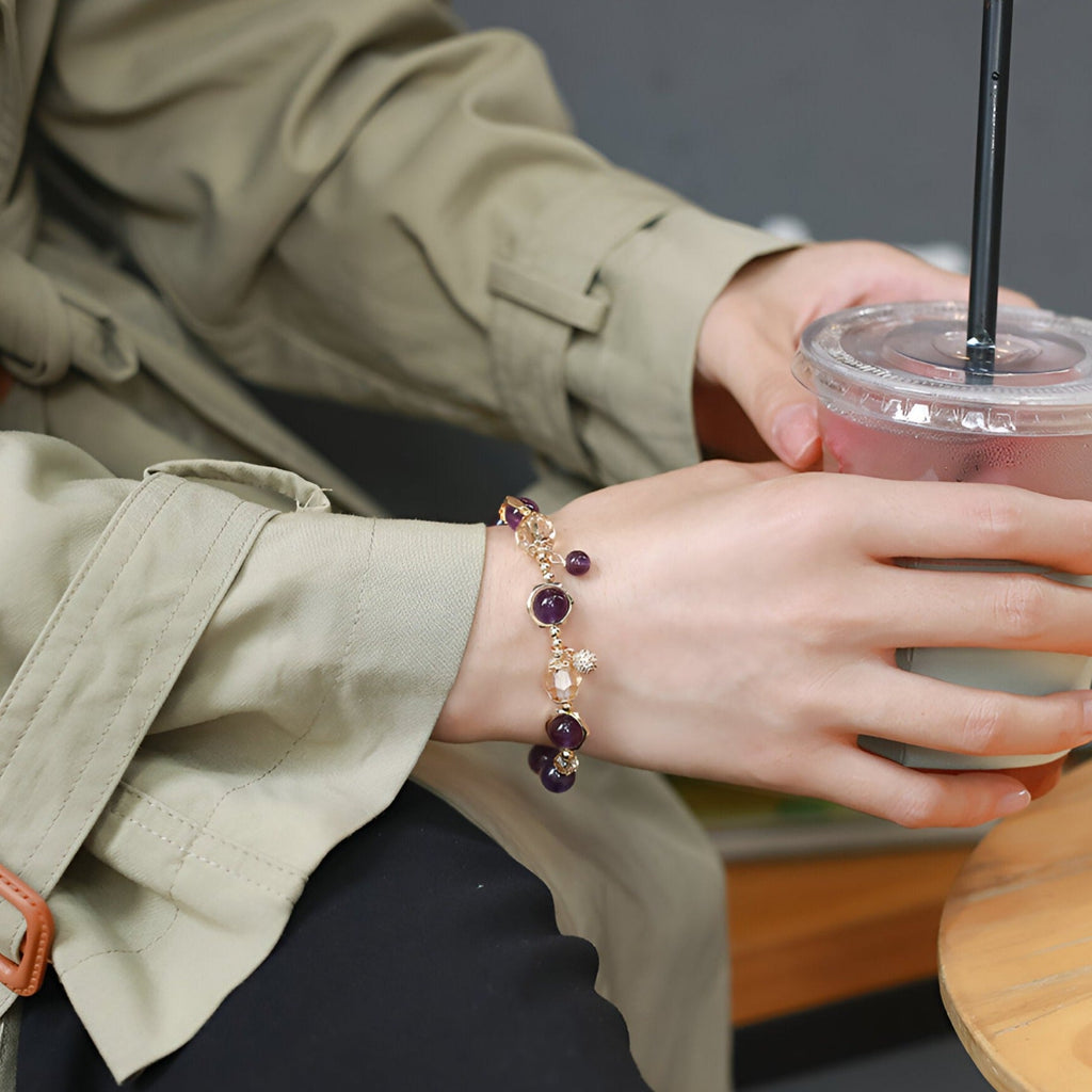 Bracelet en améthyste violet avec maillons dorés porté au poignet féminin, style élégant et délicat.
