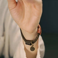 Bracelet femme en cuivre avec pendentif spirale et pierres corail orange sur chaîne métal vintage.