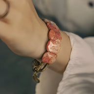 Bracelet femme en pierre de corail orange polie avec fermoir en cuivre texturé, style artisanal.