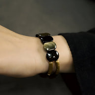 Bracelet femme en obsidienne dorée et laiton avec pierres ovales noires et dorées sur cuir noir.