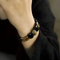 Bracelet femme en obsidienne dorée et laiton, perles rondes et cylindriques, style élégant noir et or.