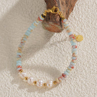 Bracelet femme perles blanches, pierres naturelles bleu clair et rose, fermoir et détails dorés.