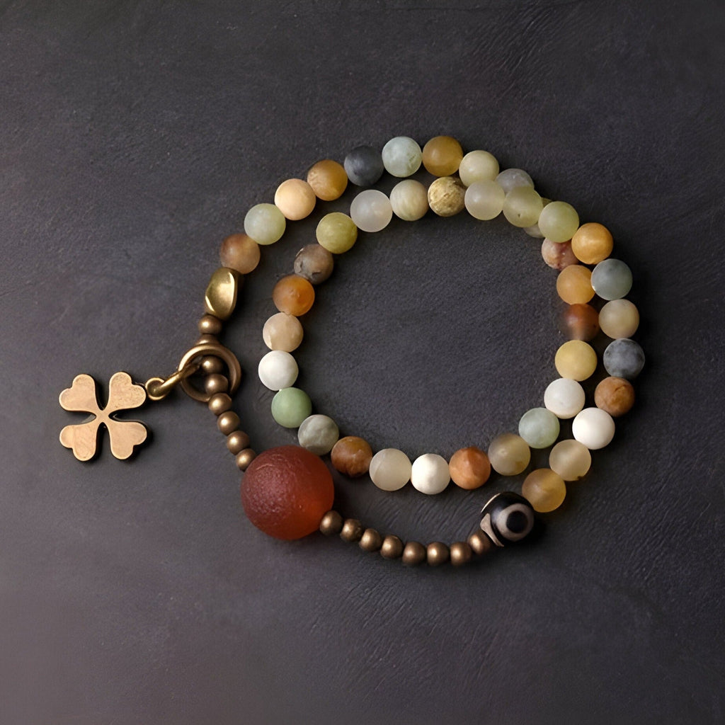Bracelet femme en pierres naturelles d'agate jaune multicolore avec pendentif trèfle doré.