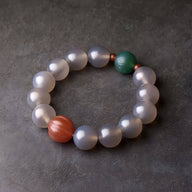 Bracelet mixte en perles d’agate blanches, avec une perle verte et une perle orangée, style méditation.
