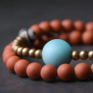 Bracelet femme en perles d'agate rouge mat avec perle centrale turquoise et perles métalliques dorées.