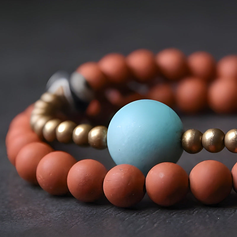 Bracelet femme en perles d'agate rouge mat avec perle centrale turquoise et perles métalliques dorées.