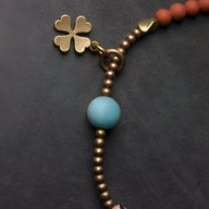 Bracelet femme avec perles métalliques bronze, perle agate bleue, breloque trèfle doré.