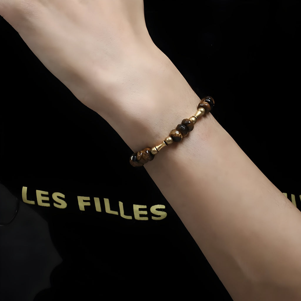 Bracelet mixte en œil de tigre et cuivre doré, perles rondes sur poignet féminin.