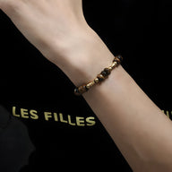 Bracelet mixte en œil de tigre et cuivre doré, perles rondes sur poignet féminin.