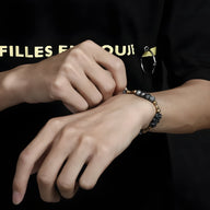 Bracelet mixte en pierres naturelles grises et cuivre, style Andy, porté au poignet.