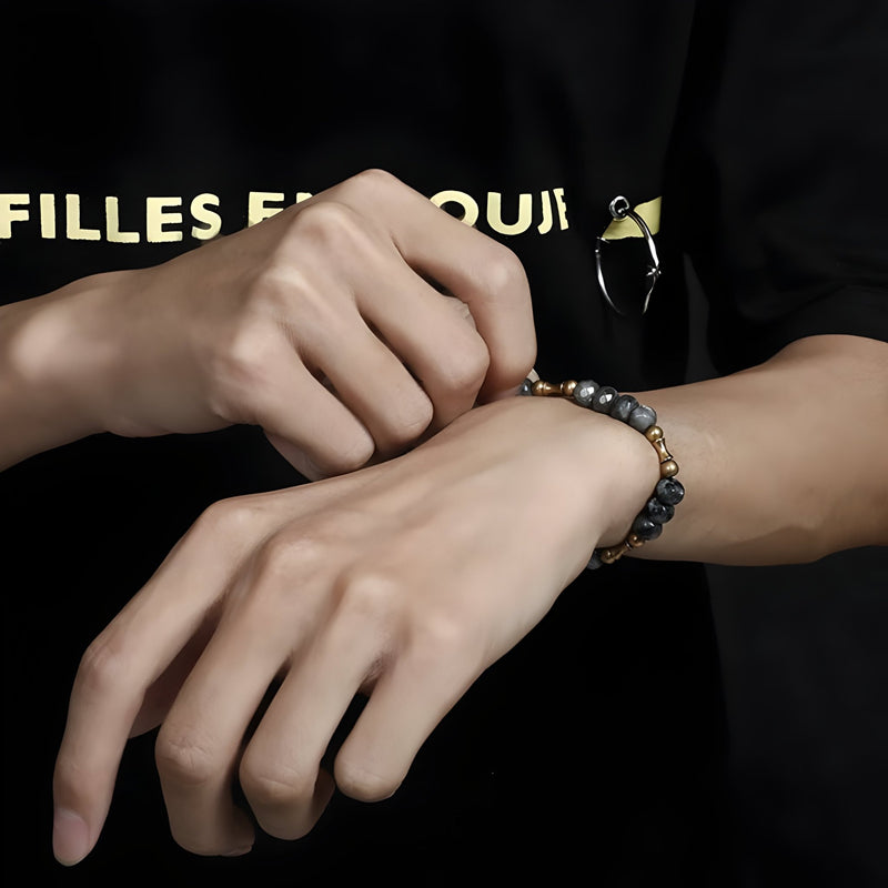 Bracelet mixte en pierres naturelles grises et cuivre, style Andy, porté au poignet.