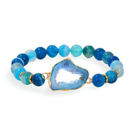 Bracelet en agate bleu aux pierres naturelles irrégulières avec pendentif central doré et bleuté.