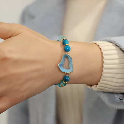 Bracelet Paulina en agate bleu avec pierres naturelles irrégulières et pièce centrale ajourée en forme géométrique.