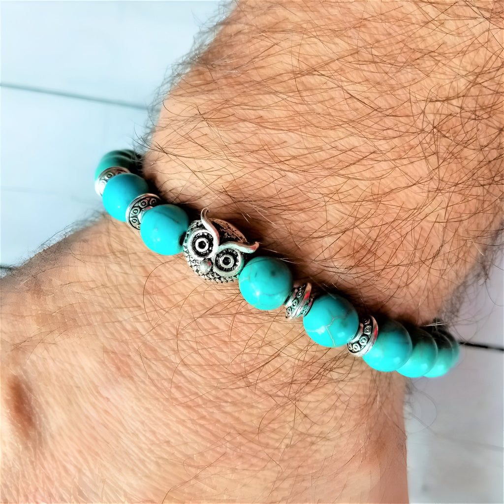 Bracelet mixte en perles turquoise avec hibou protecteur en métal argenté sur poignet.