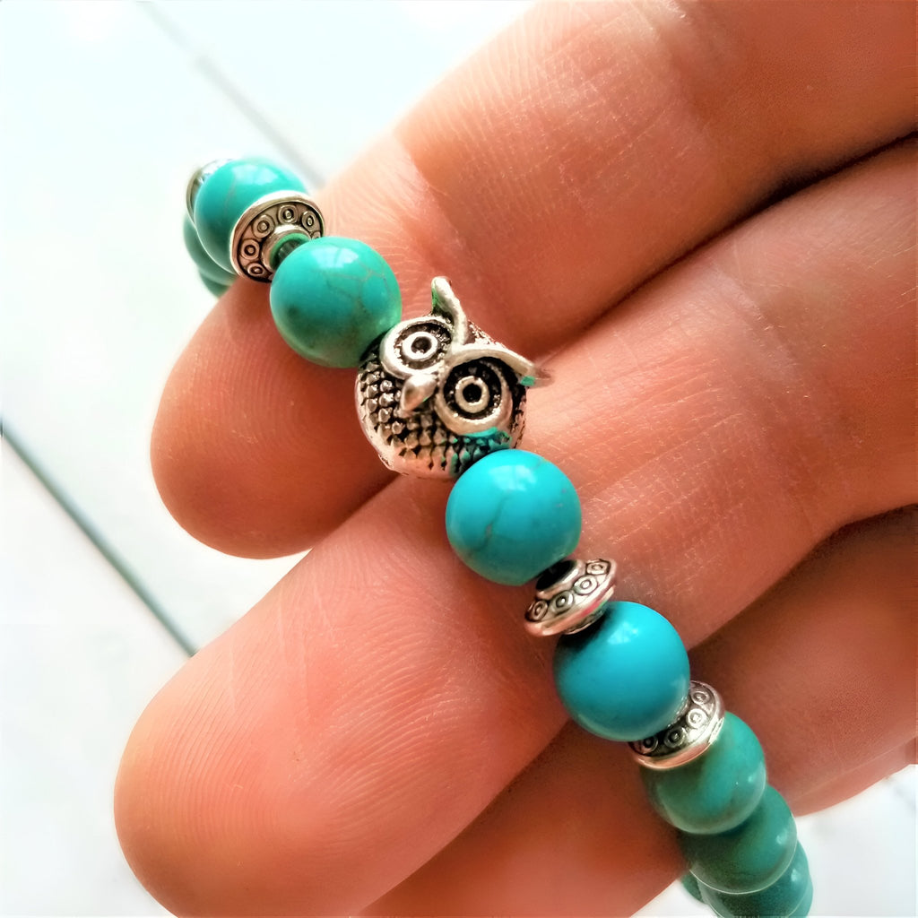 Bracelet mixte en pierres turquoise rondes avec perles argentées et pendentif hibou protecteur détaillé.