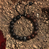 Bracelet masculin en pierre volcanique noire et jaspe marron, ornement en métal spartiate au centre, ficelle noire ajustable.