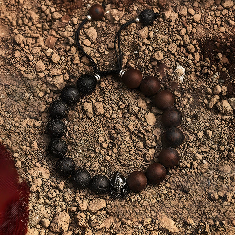 Bracelet masculin en pierre volcanique noire et jaspe marron, ornement en métal spartiate au centre, ficelle noire ajustable.