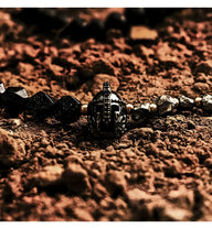 Bracelet noir en pierres naturelles avec ornement casque spartiate en métal sur fond terreux.